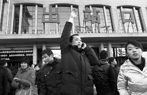 昨日,北京站前,一位刚抵京的旅客高举手臂向接站的人示意.