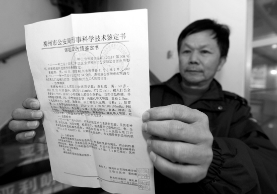 被打门卫谢祖成展示"伤情鉴定书.新华社发(李斌摄)