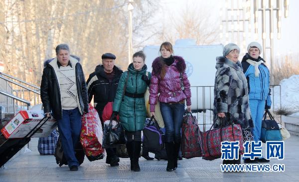 2月19日,前来黑龙江省黑河市的游客提着在该市采购的商品准备