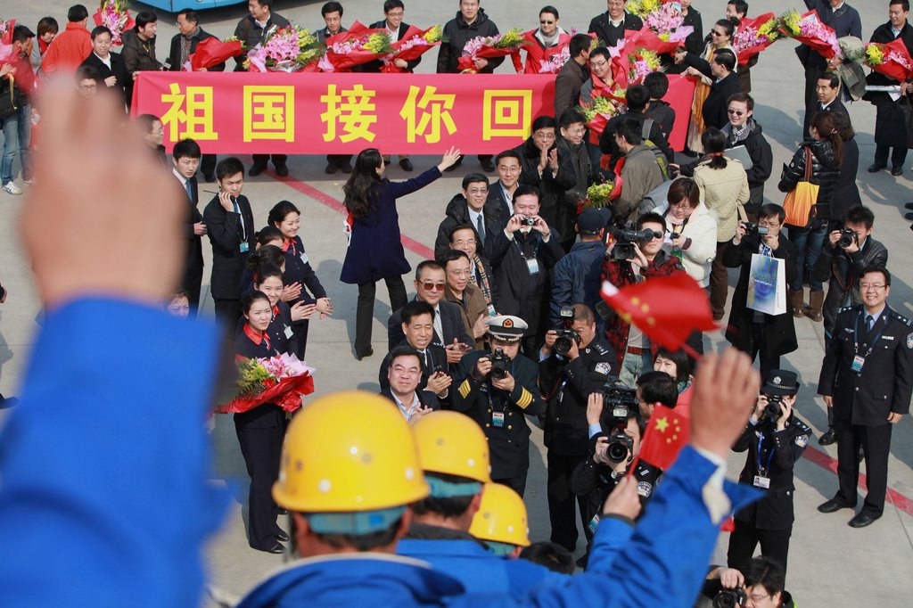 2011年3月5日,从利比亚撤回的中国人员走下飞机旋梯,向迎接人员挥手