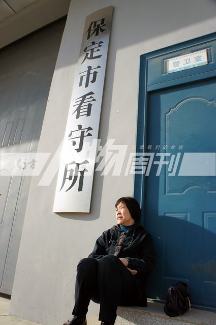 杨惠贤坐在看守所巨大铁门边,她要在看守所门前看儿子一眼(刘珏欣)