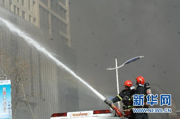 4月9日,两名消防队员手持消防枪在向失火处喷水.新华社记者 王博 摄