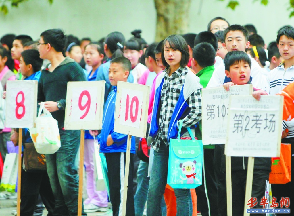 在青岛实验初中,报名的学生举着临时的牌子排队入场.