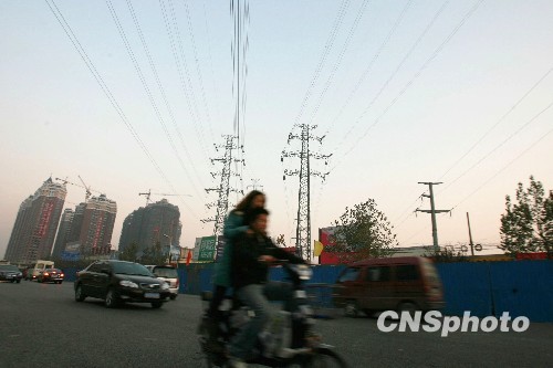 图为郑州市民骑电动车从一处密集的电网下走过（资料照片）。中新社