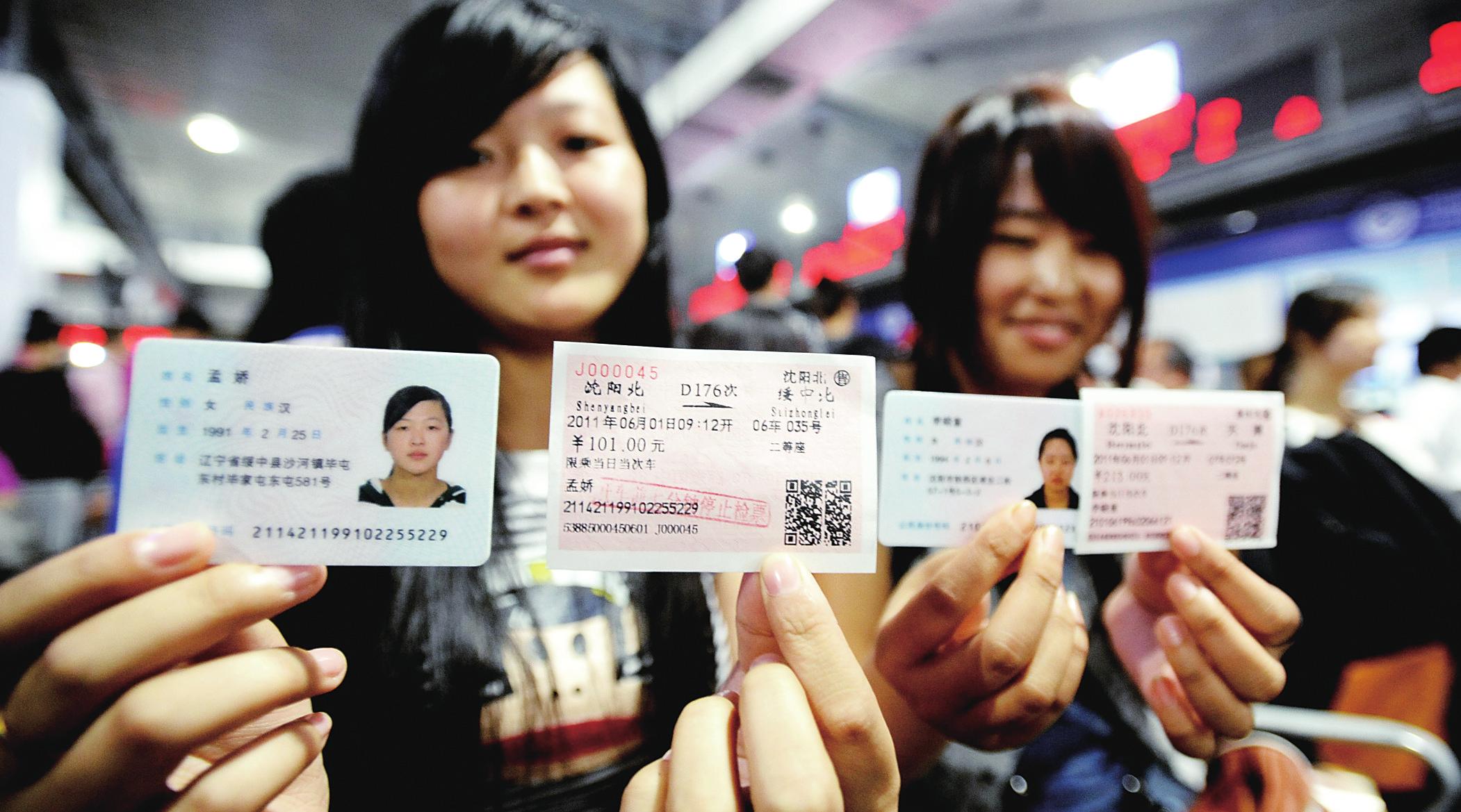 图为两名旅客在沈阳北站展示自己的身份证和动车车票.