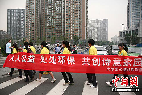 高校大学生志愿者拉着横幅在闹市区普及环保理念.