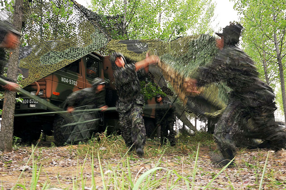 身着新型伪装服的士兵对指挥所进行伪装(吴苏琳摄)