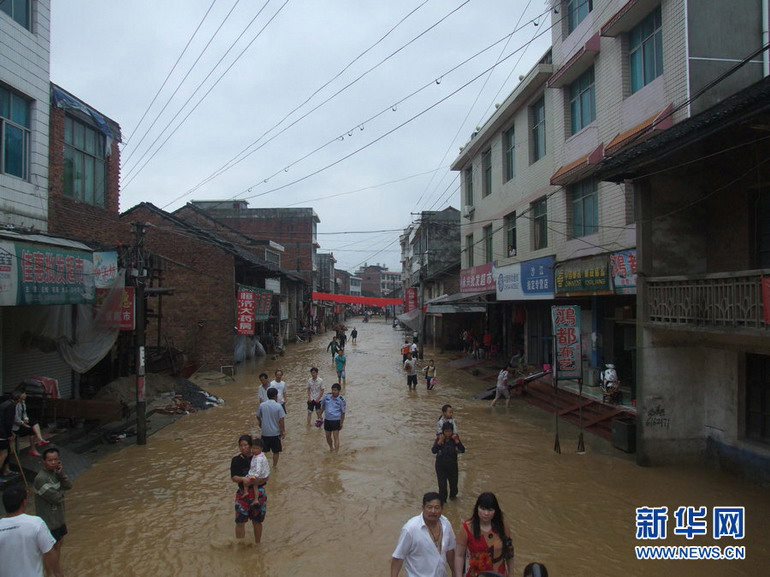 6月10日,湖南省娄底市新化县西河镇沙江村村民走在被雨水淹没的道路上