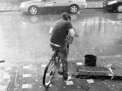 6月11日15时左右,北京西城突降阵雨,一位骑自行车人躲闪不及被淋湿.