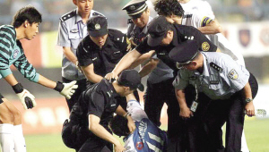 李玮锋（右白衣者）试图把小球迷和警察分开