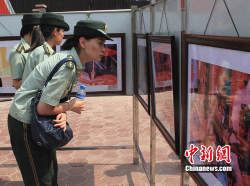 三名消防女兵正在欣赏参展摄影作品 赵昕 摄
