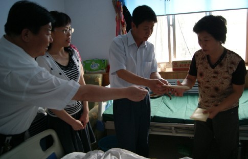 叶县"黑脚"怪病少年张亚伦的母亲娄苏芹接过叶县县长古松送来的救助金