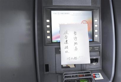 4台自动取款机吐钞口被胶水封住,旁边贴着"设备遭破坏,暂停服务"的
