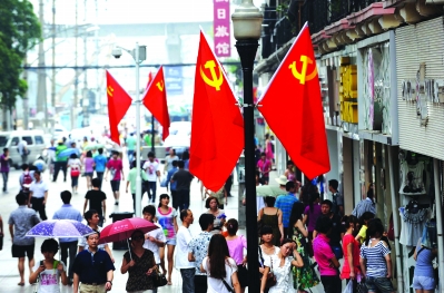 昨日,江汉路步行街管理办公室工作人员在灯杆,天桥上悬挂出90面党旗