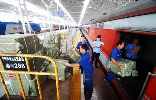 在江西九江市火车站站台,中铁快运的工作人员将快递包裹装上客车行李