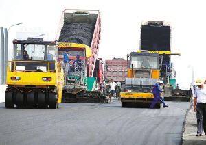 多台筑路机械正在路面加紧摊铺沥青