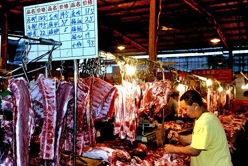 7月14日,一位猪肉零售商在福州市一农贸市场整理自己的肉铺迎候顾客.