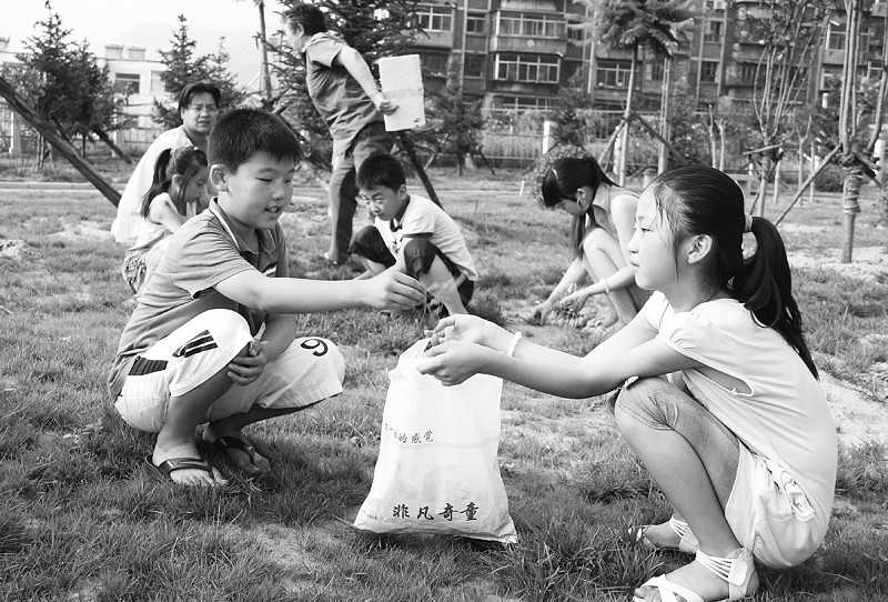 孩子们正在清理社区绿地,通过劳动增强"社区是我家,建设靠大家"的公德