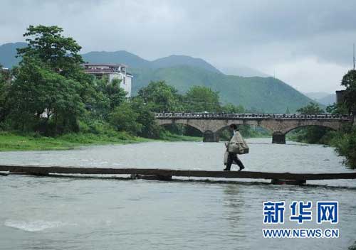7月19日，罗细英背着邮包经过陈坊乡的一条小河。
