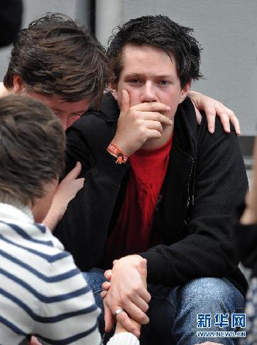 7月26日，在挪威奥斯陆大教堂旁，于特岛枪击案幸存者、16岁少年松雷·尼尔森（右）和家人、朋友哀悼死难者。新华社记者王庆钦摄