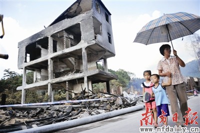 村民从被毁楼房旁边经过。