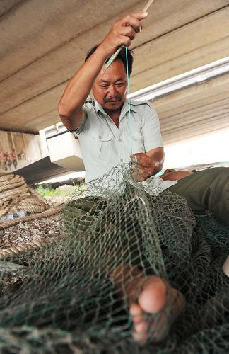 8月31日,一名渔民在天津市滨海新区蔡家堡码头补渔网.