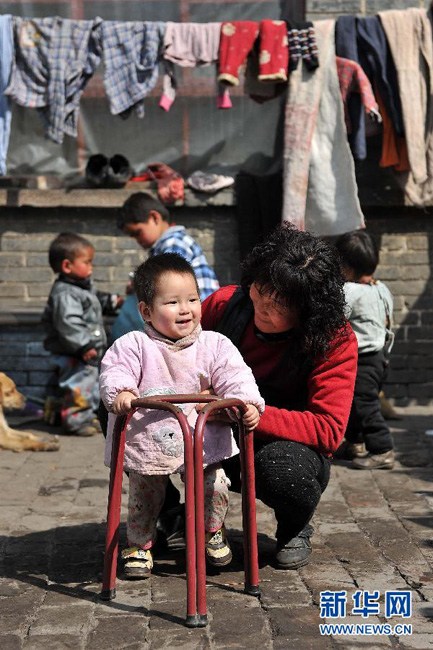李艳萍在教一个11个月大的孩子学走路（3月19日摄）。詹彦 摄 新华网