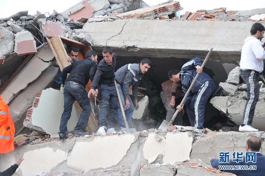 10月23日，在土耳其东部凡省，当地居民用铁锹清理废墟。