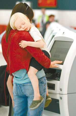 10月31日,一名妇女抱着孩子在悉尼的国际机场办理登机卡. 新华社/法新