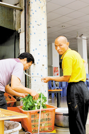 饭店老板洗菜,男子在旁帮忙.