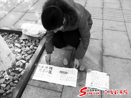 这名红衣女子在泉北大街的便道上铺设手写标语,欲靠乞讨实现"三梦".