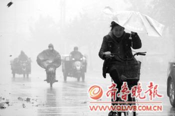 雾很大,一位市民在风雨中前行,艰难的控制着手中的雨伞.