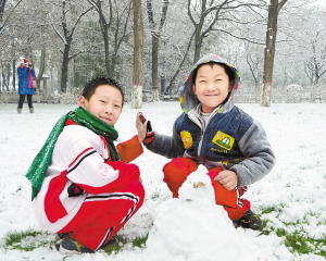 ②两个小朋友在公园堆雪人,感受快乐. 詹新城 摄