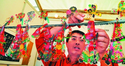 皮影艺人在广西南宁国际会展中心把作品挂在绳