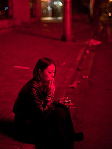 浓妆的女子坐在马路边的台阶上抽烟打电话.铃声如泣,惊落泛黄的秋叶.