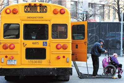 12月9日，一名校车司机在美国纽约市布鲁克林区的一所学校门前帮助一名坐轮椅的孩子上校车。 新华社发