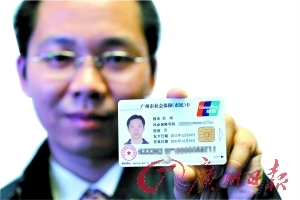广州首位领取新版社保卡的市民翁斌在展示自己