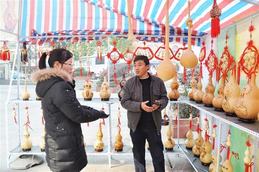 农村新报讯 图为：刘成华右在向顾客介绍工艺葫芦产品