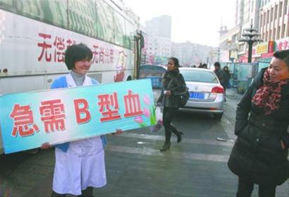 昨日，葫芦岛市步行街上，中心血站采血服务科科长穿着白大褂手举告示求血。 记者 冯玉兴 摄