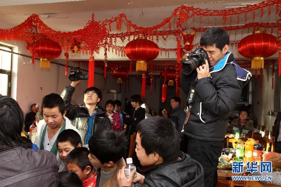 1月22日，新华社记者王建华（右）在位于北京市顺义区南法信镇的大江洼村的“光爱之家”采访流浪儿童们的年夜饭。