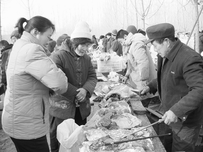图为山东省莒南县文疃镇的年集上,农民正在选购新鲜猪肉.