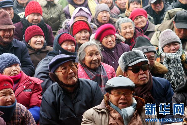 1月30日,开封市东郊乡边村村民在家门口看戏.