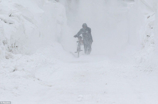 在罗马尼亚,一名行人推着自行车在暴风雪中艰难前行.