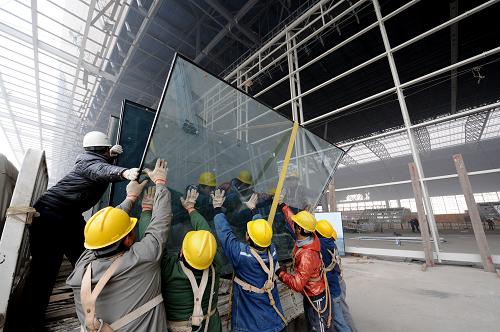 2月14日,几名工人在向京广客专郑州东站候车室内搬运玻璃.