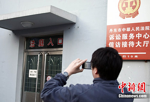 15日,一名记者在辽宁省丹东市中级人民法院外