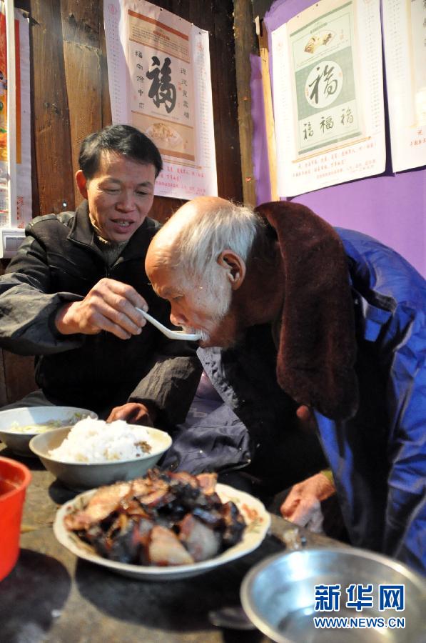 2月10日,庖田村村民粟万胜在姚祖纯家里照顾老人吃饭.