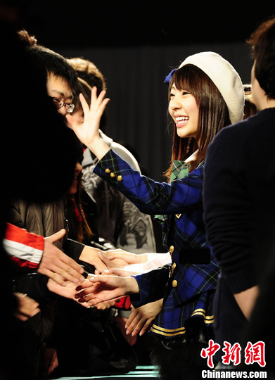 2月18日,一名日本人气流行组合"akb48"的成员在北京与"粉丝"们握手.