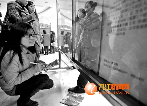蔡杰摄   3月3日,在九江专场就业招聘会上,求职者查看招工海报.