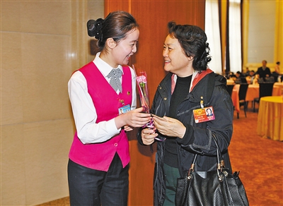 3月8日清晨,京西宾馆女服务员为一名女代表送上鲜花,共贺节日.