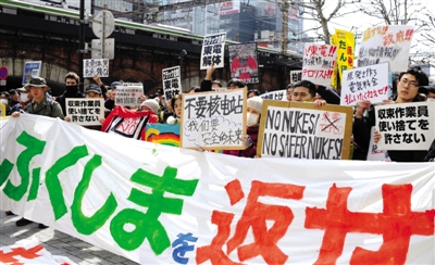 3月11日，在日本东京电力公司前，市民打出“还我福岛！”、“不要核电！”等标语。新华社记者 马平 摄